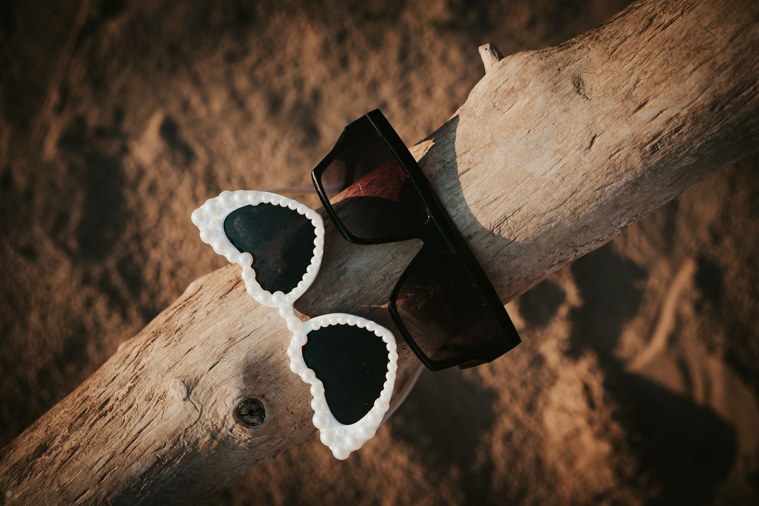 Black and white satin wedding shoes photographed on a wooden surface with warm dramatic lighting.