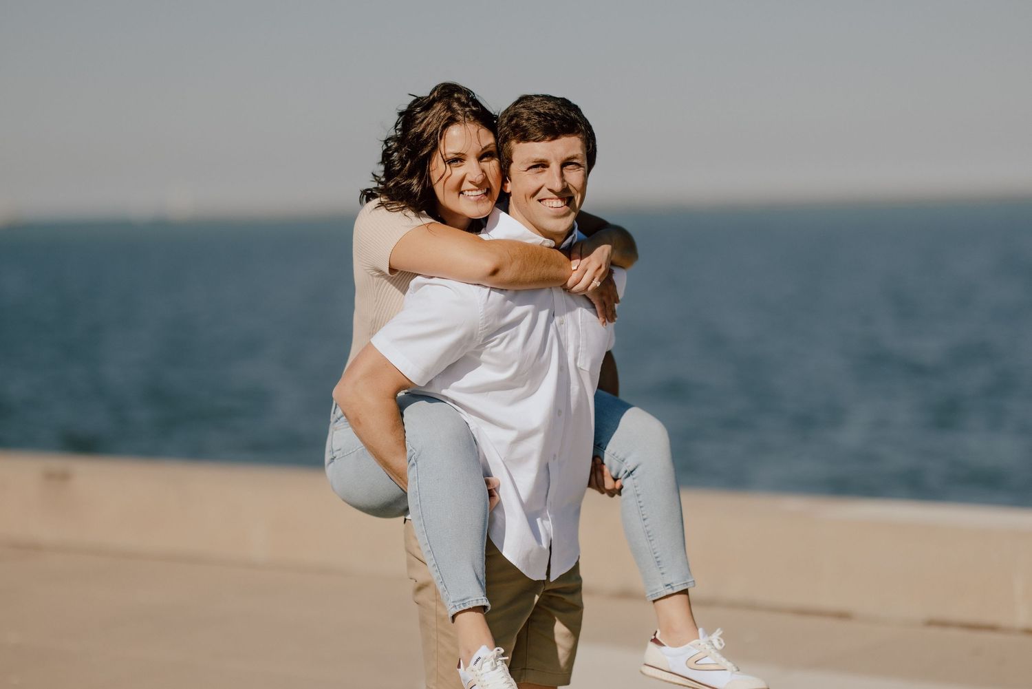Young couple sharing a romantic moment on a sandy beach with the ocean in the background during golden hour.