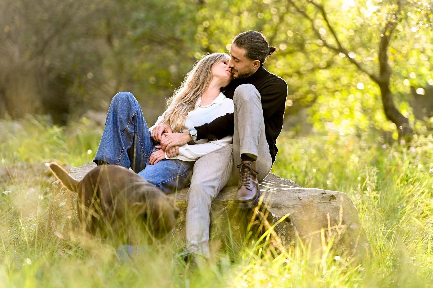 A couple shares romantic moments together while relaxing in a sunlit meadow during a spring afternoon.