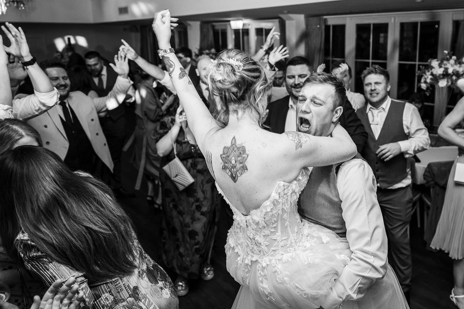Kelham House wedding photographer image of groom lifting the bride on a crowded dance floor with guests cheering and arms raised