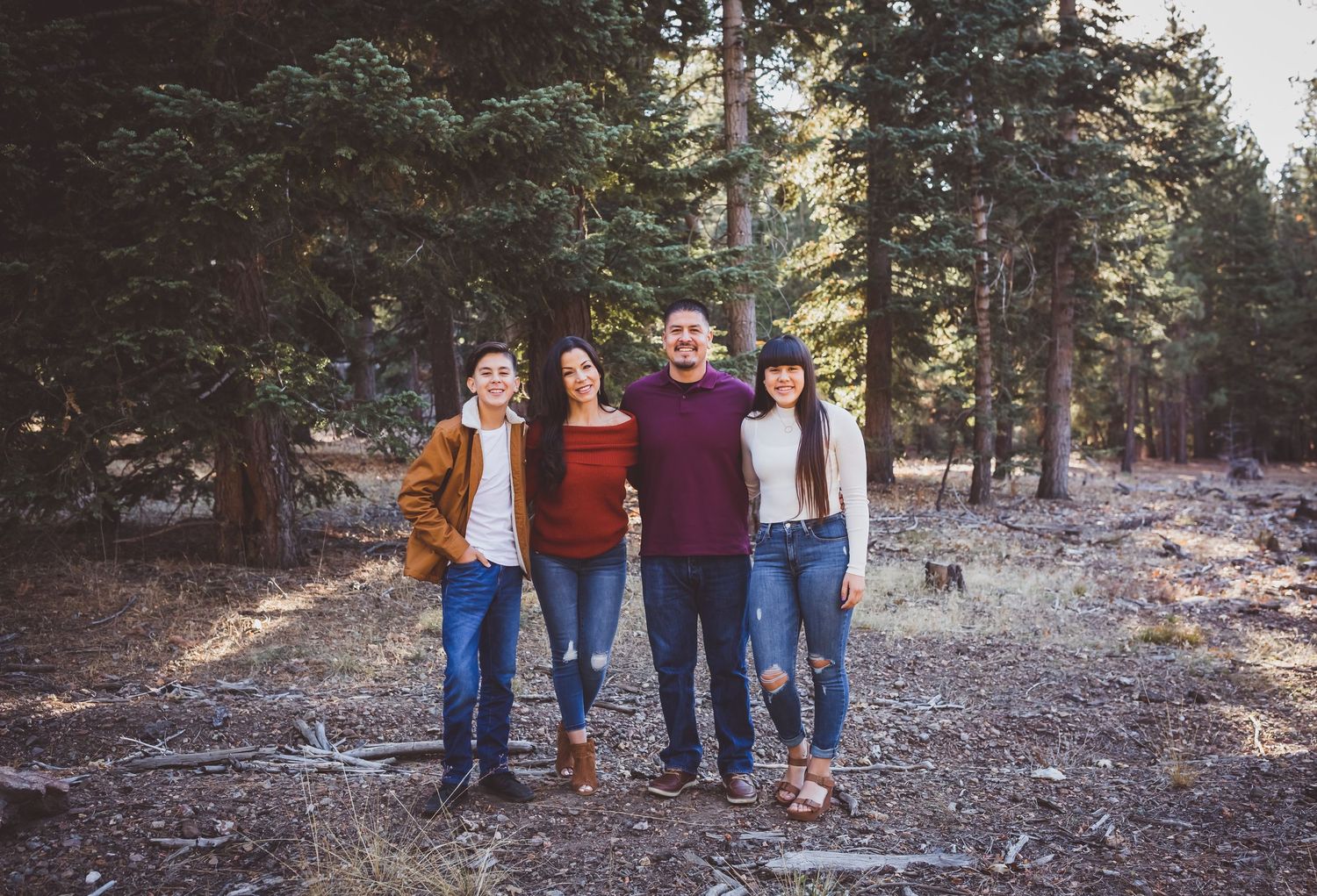 Group of holidaymakers posing in a scenic evergreen forest on a sunny autumn day.