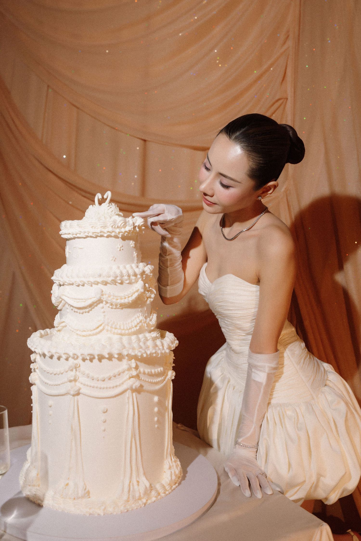 A three-tier white wedding cake with elegant piped details being photographed from multiple angles.