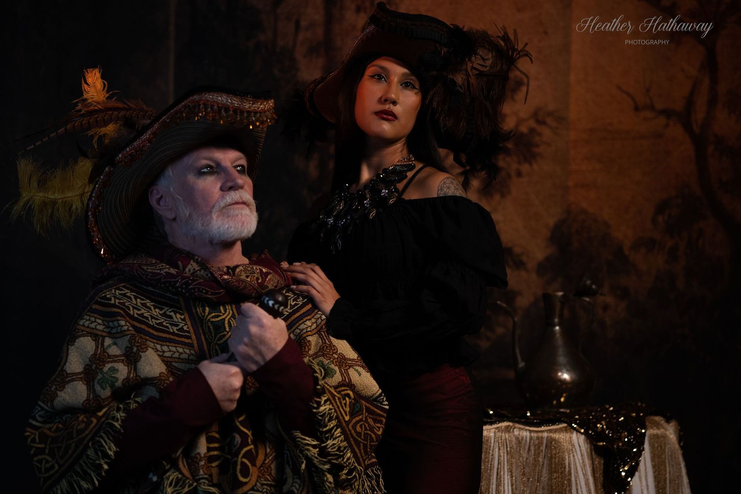 Two people dressed in Victorian Gothic costumes pose dramatically in dark moody lighting with antique decorative elements.