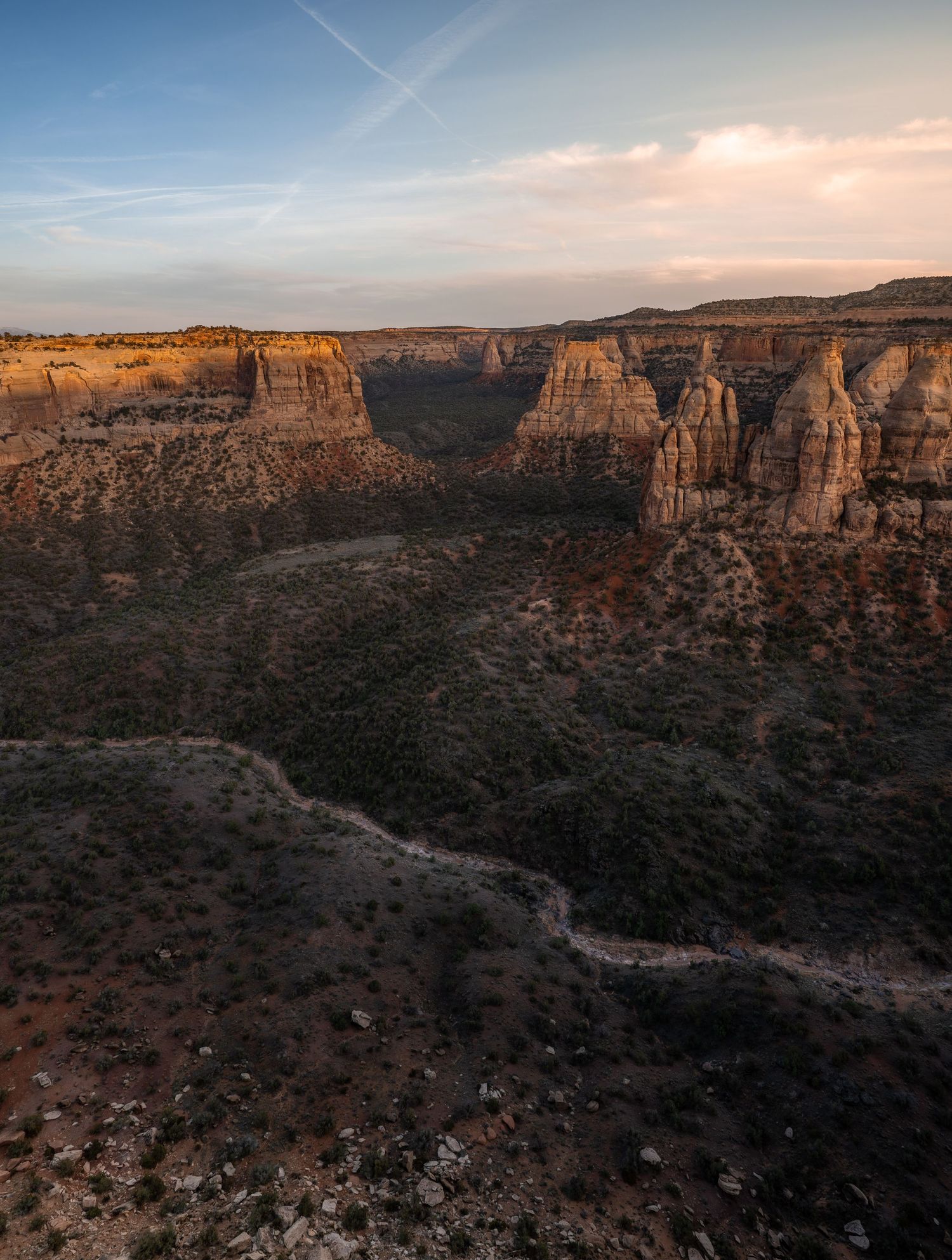 Panoramic aerial view of red rock canyons and desert landscape at sunset in Colorado National Monument.
