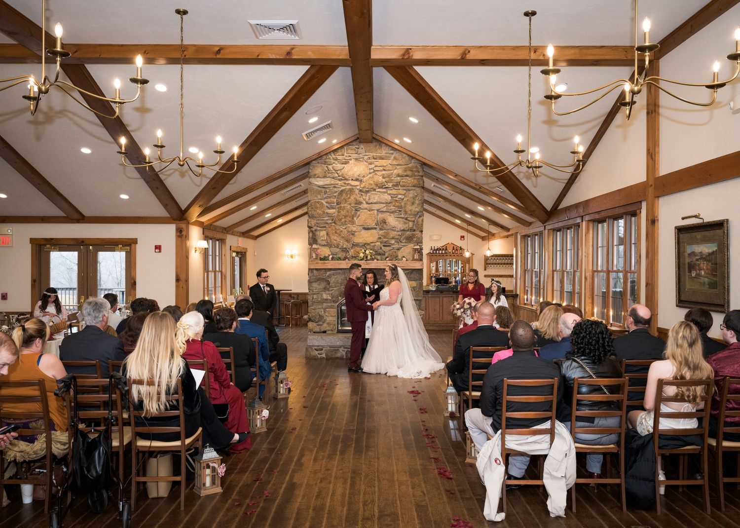 Newlyweds share an intimate moment outdoors with autumn foliage and rustic architecture in background.