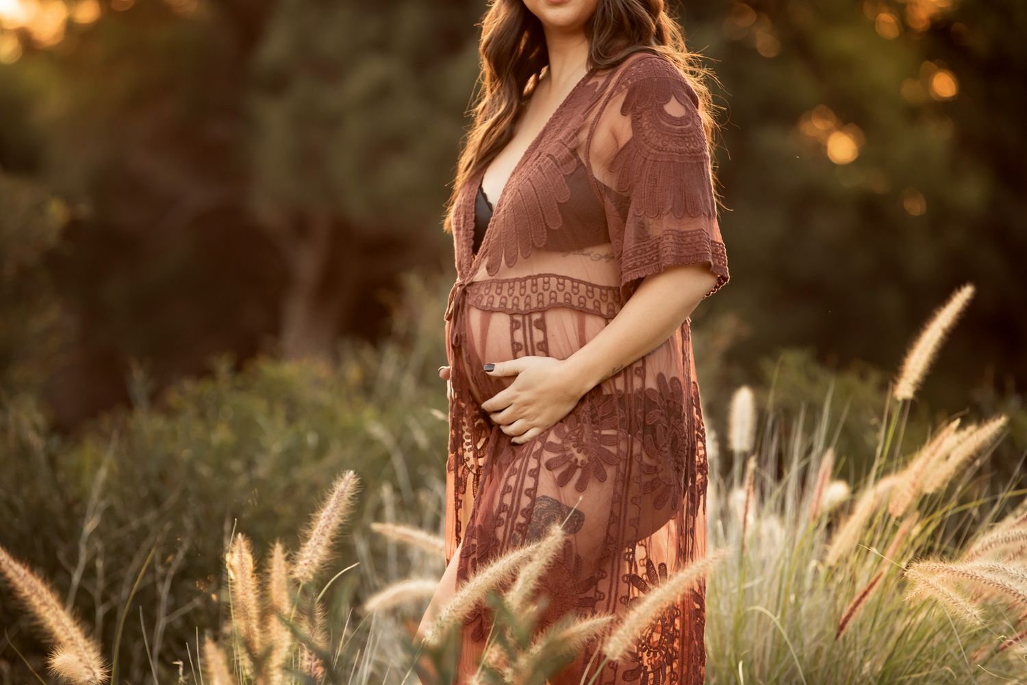 Pregnant woman in golden field at sunset beside photographer TM Channon bio, specializing in timeless maternity portraits.