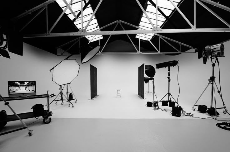 Professional photography studio interior in black and white with lighting equipment and white seamless backdrop.