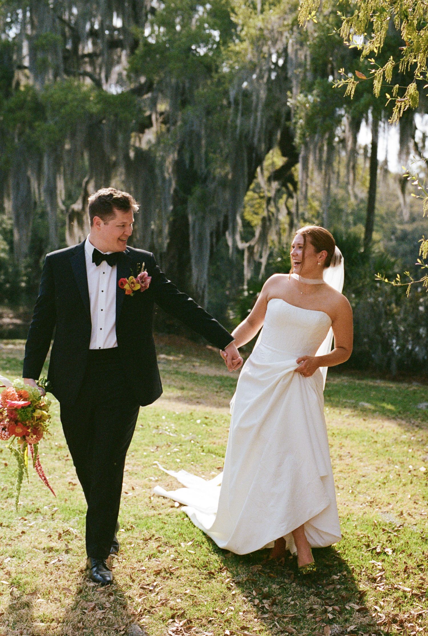 A wedding ceremony in a wooded setting with white draped fabric decor and a Persian rug aisle runner.