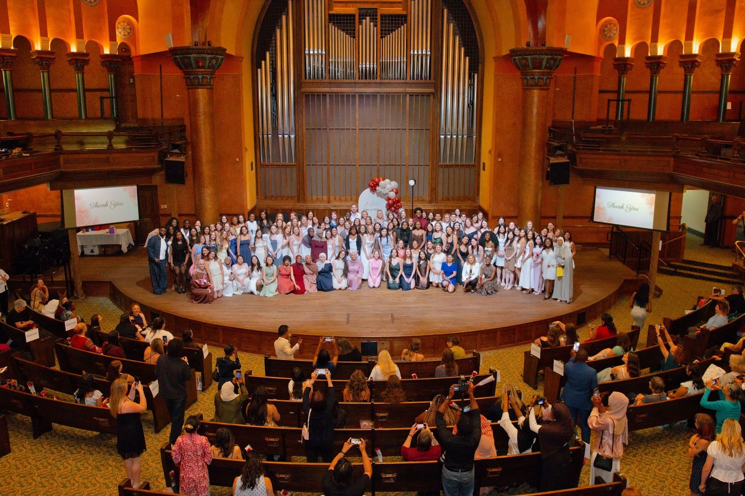 Large group photo of people gathered in an ornate church hall with pipe organ backdrop.