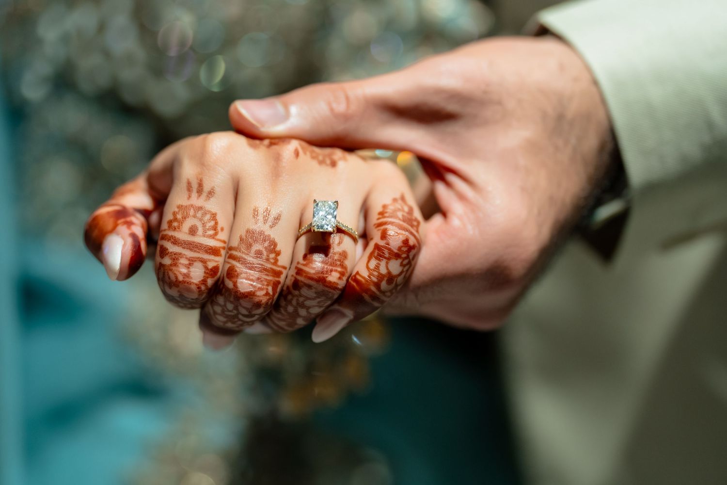 Close-up of a hand adorned with intricate henna mehndi design and a diamond engagement ring on wedding day.