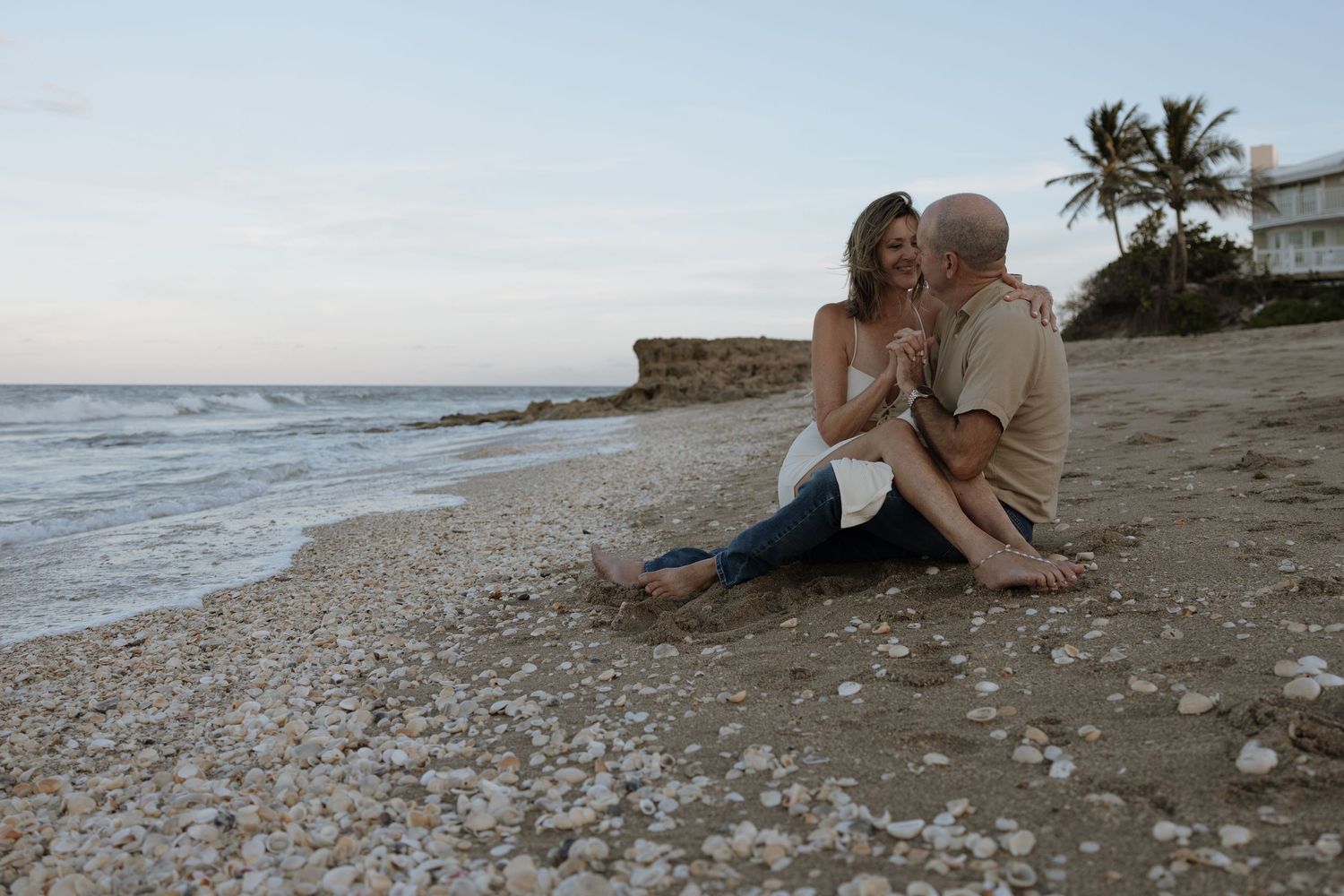Romantic couple sharing intimate moments on a peaceful beach at sunset.