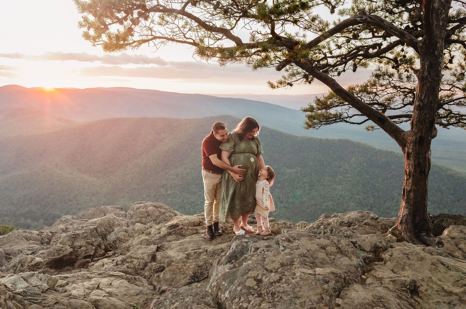 Gorgeous sunset photograph of pregnant mama, father, and toddler against a golden sunset at the breathtaking Raven's Roost Overlook.
