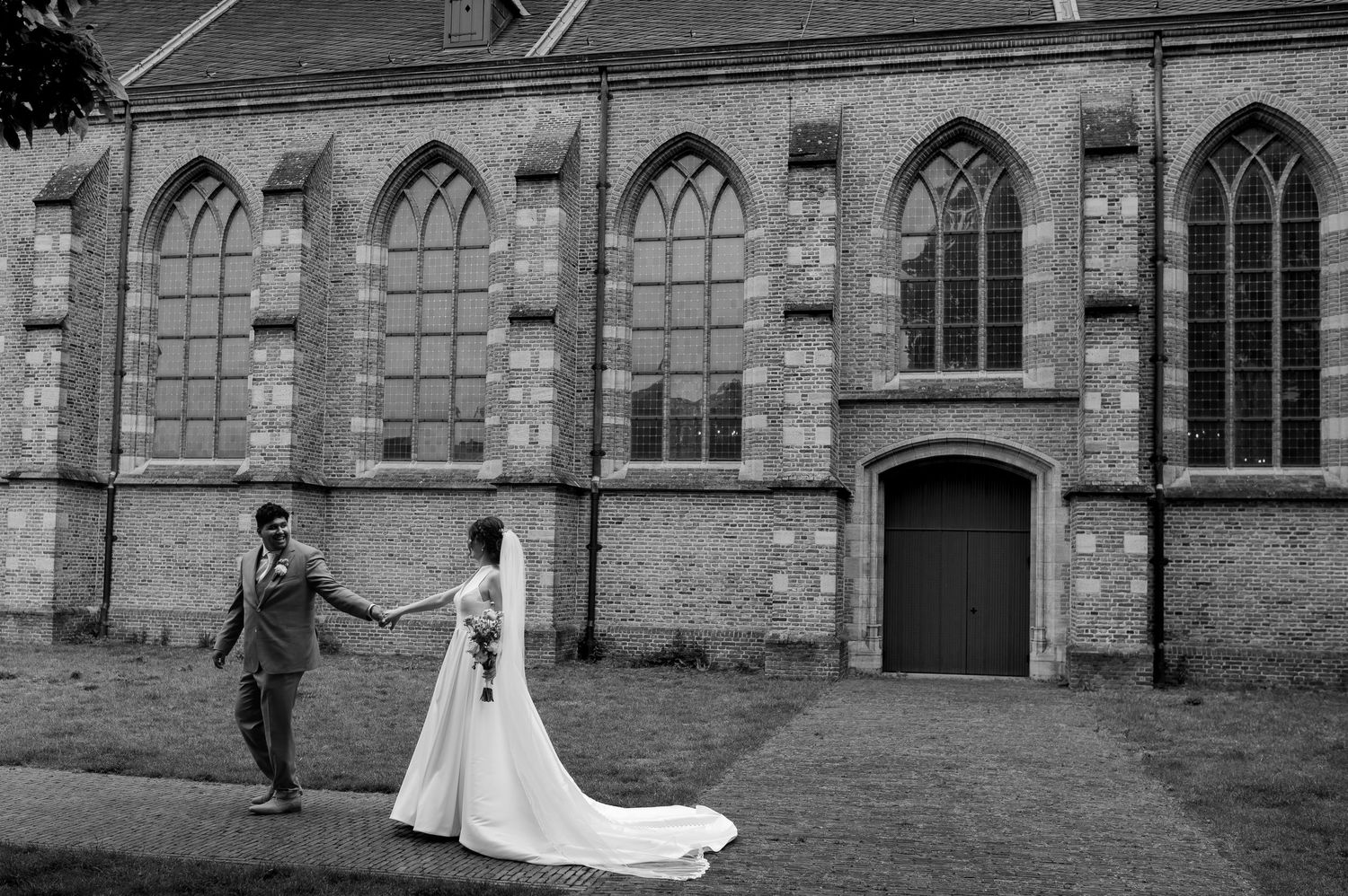 Spontane trouwfoto van bruid en bruidegom hand in hand op locatie in Huizen