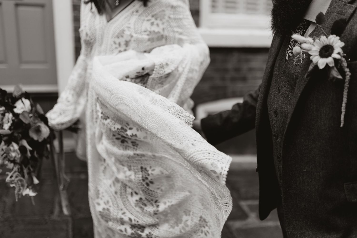 A bride and groom hold hands during their first dance at an indoor wedding reception.