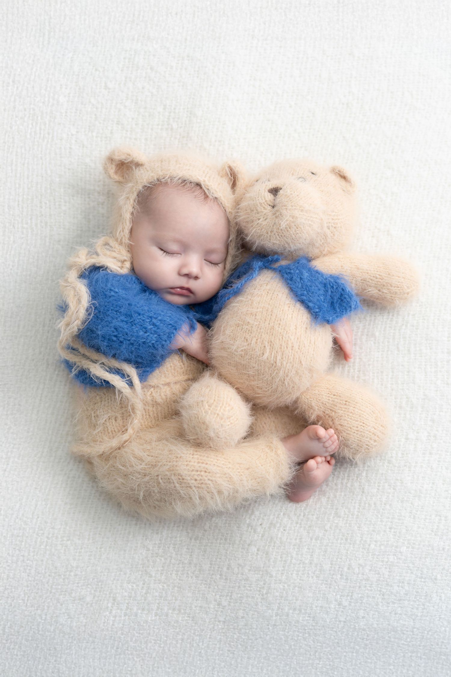 Professional newborn photographer in Dubai carefully posing a baby with safe props and gentle lighting for a cozy photoshoot.