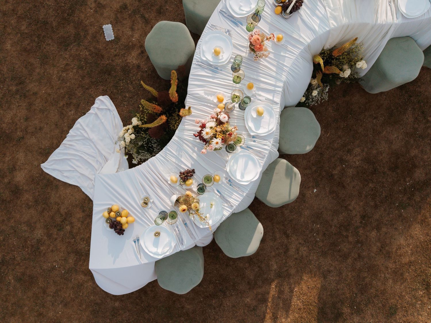 Overhead view of an elegant crescent-shaped wedding reception table set with place settings and floral arrangements.