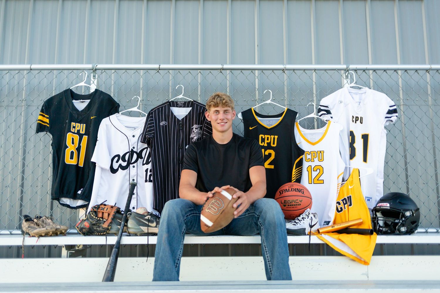A display of sports jerseys and equipment including basketball, football, and helmets arranged on bleacher seating.
