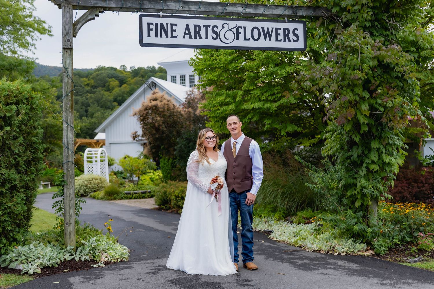 Wedding ceremony takes place under a rustic wooden pavilion with exposed beams and scenic view through archway in background.