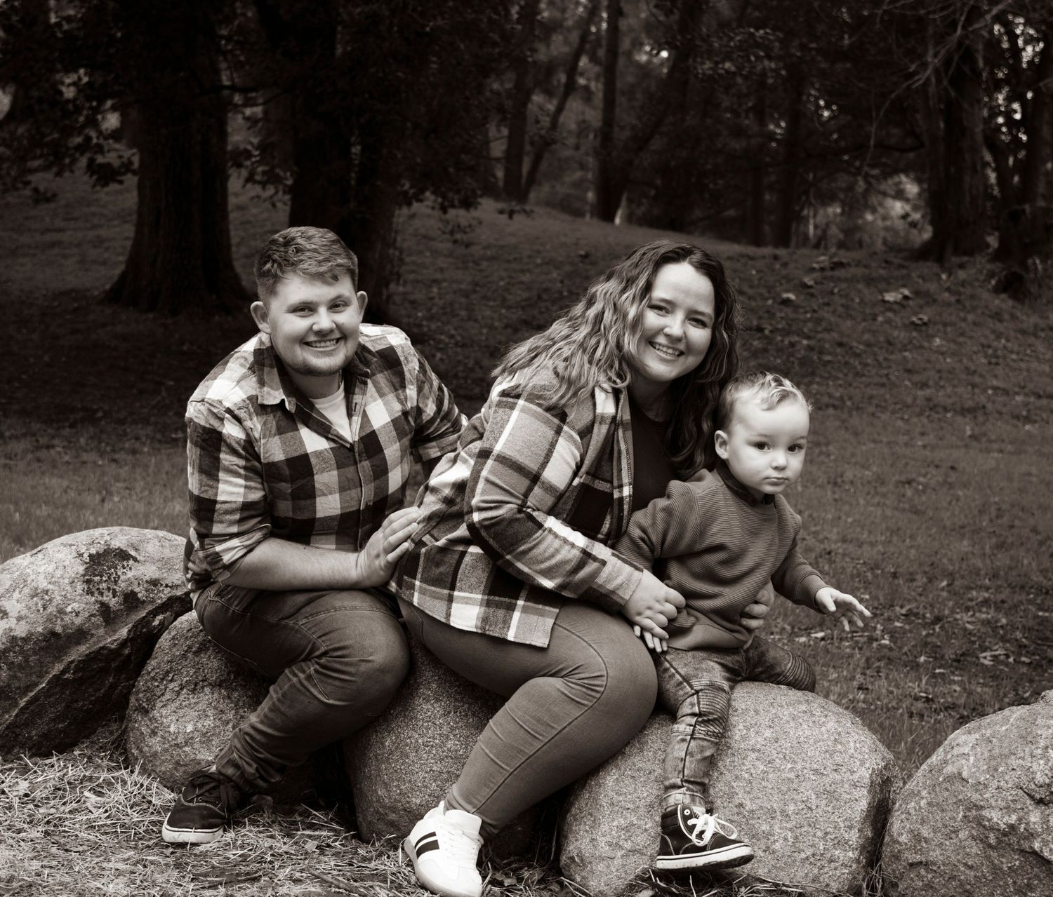 Family group relaxing outdoors on rocks in black and white photography.