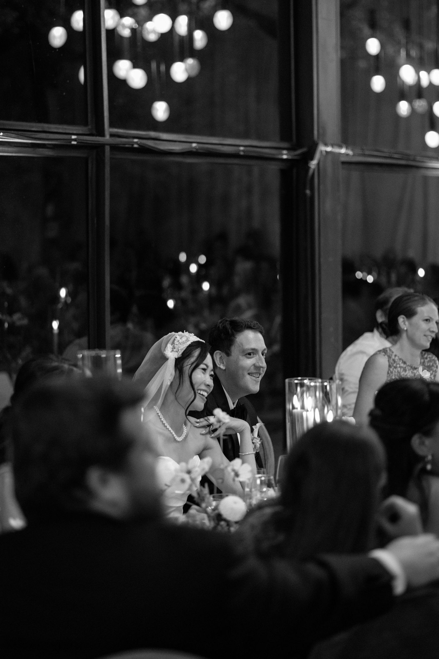 A wedding couple shares romantic moments under willow trees surrounded by elegant white and pink floral arrangements.