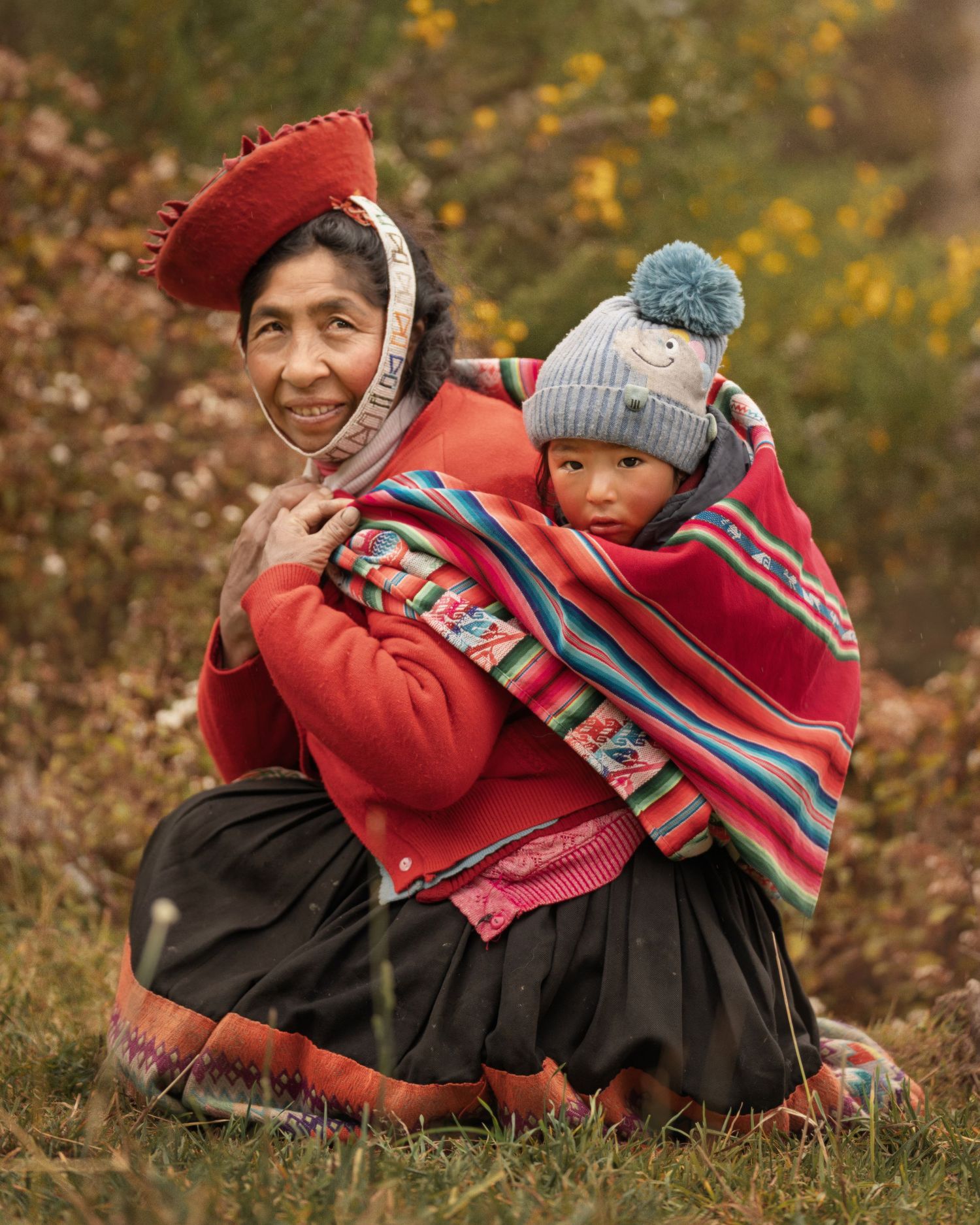Traditional Peruvian clothing shown in autumn setting with vibrant red textiles and woolen accessories.