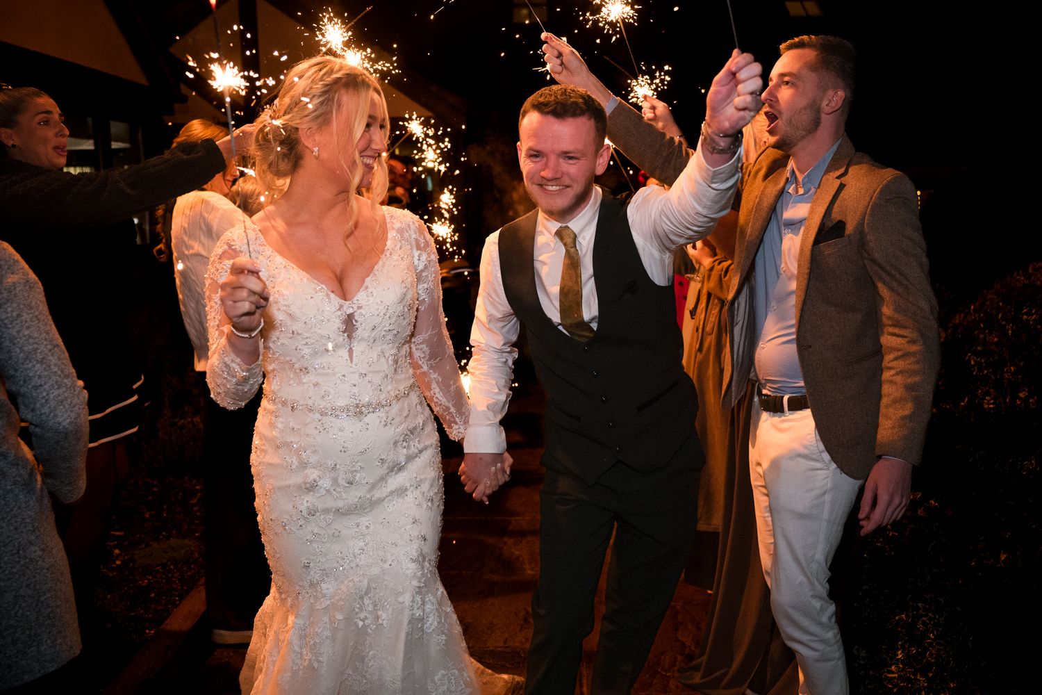 Wedding guests dance and celebrate on a dimly lit dance floor during an evening reception.