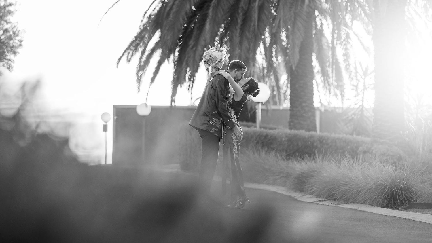 Groom walking kissing his Bride wearing a traditional red Chinese wedding dress from 'East meets Dress' at sunset at De Bortoli Rutherglen.