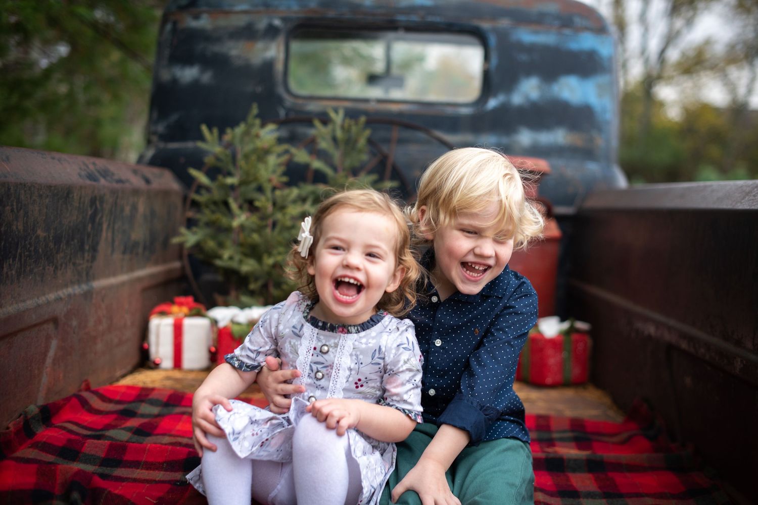 Two people with arms raised celebrating among snowy Christmas trees.