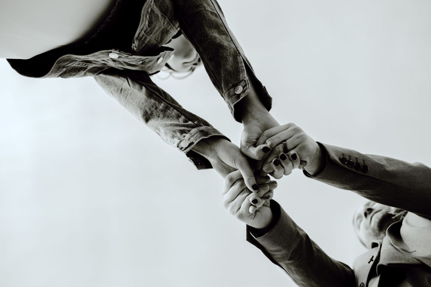 Dramatic black and white image of hands reaching out and grasping one another.