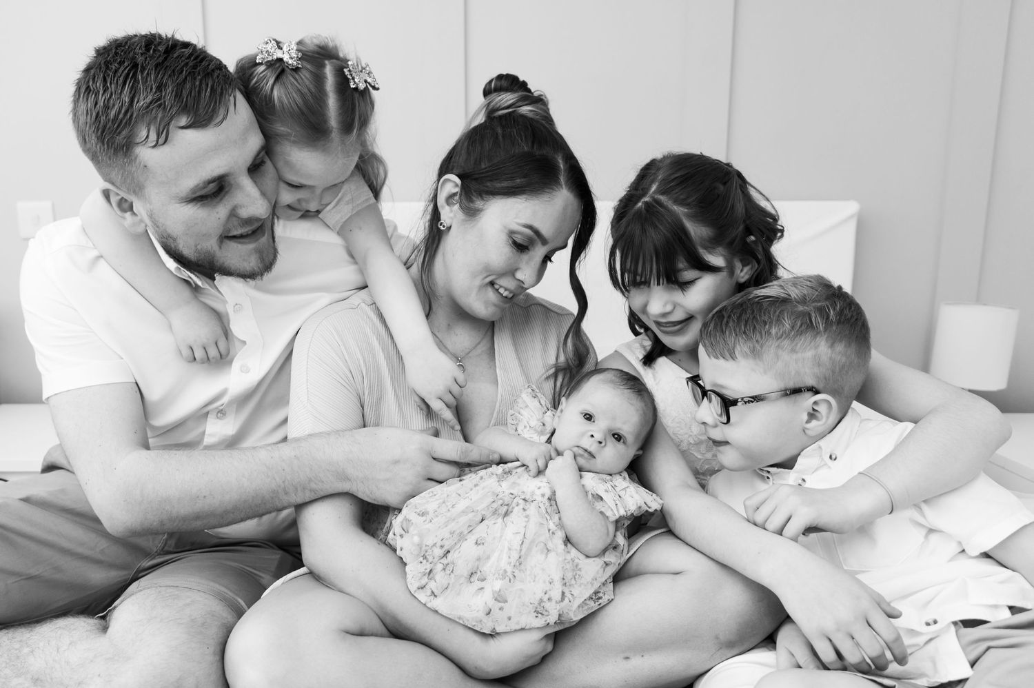 Black and white lifestyle newborn photography session with family on white bedding.