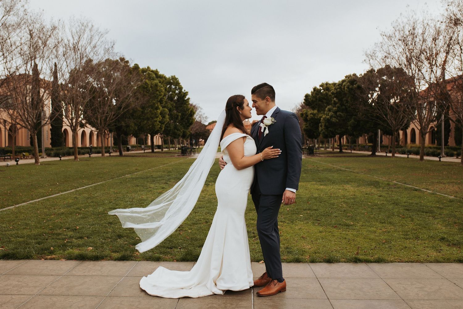 A romantic wedding couple shares intimate poses on a grassy campus pathway at Liberty Station in San Diego.
