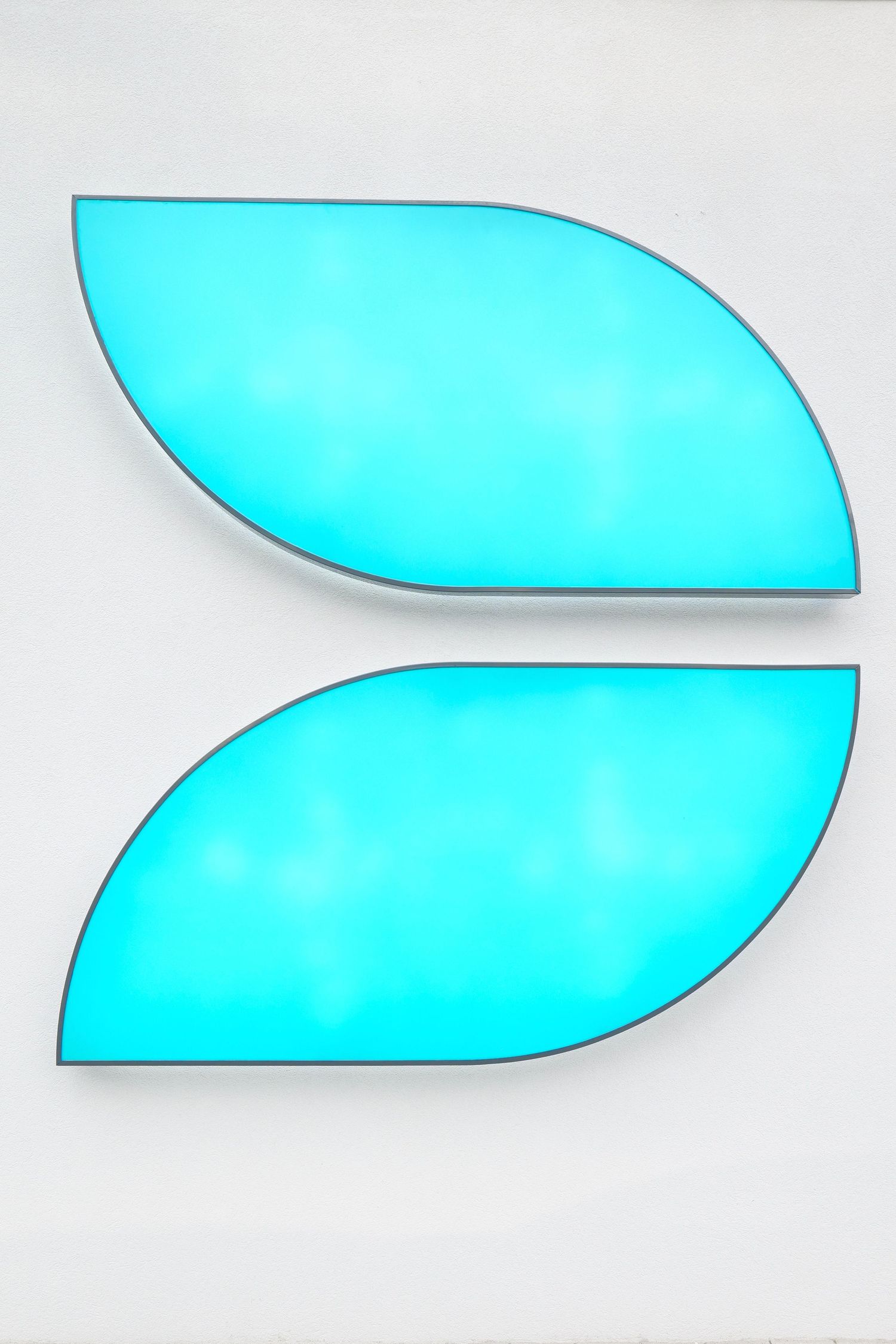Two glowing cyan turquoise leaf-shaped illuminated panels mounted on a white wall forming a modern logo design.