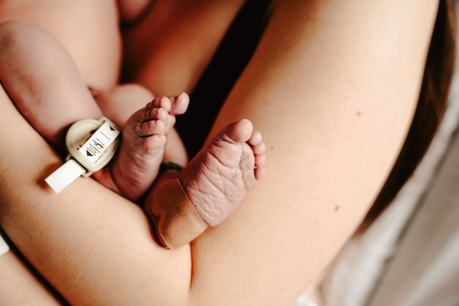 Close up detail of tiny newborn baby feet and toes with hospital bracelet.