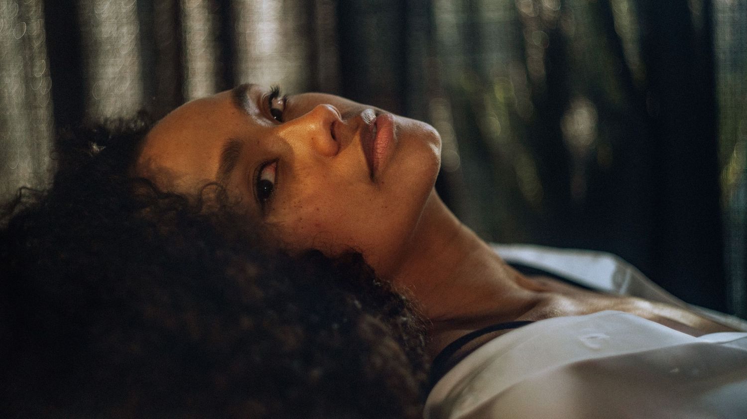 A close-up portrait of Priscilla, framed by soft natural light, with a contemplative expression.