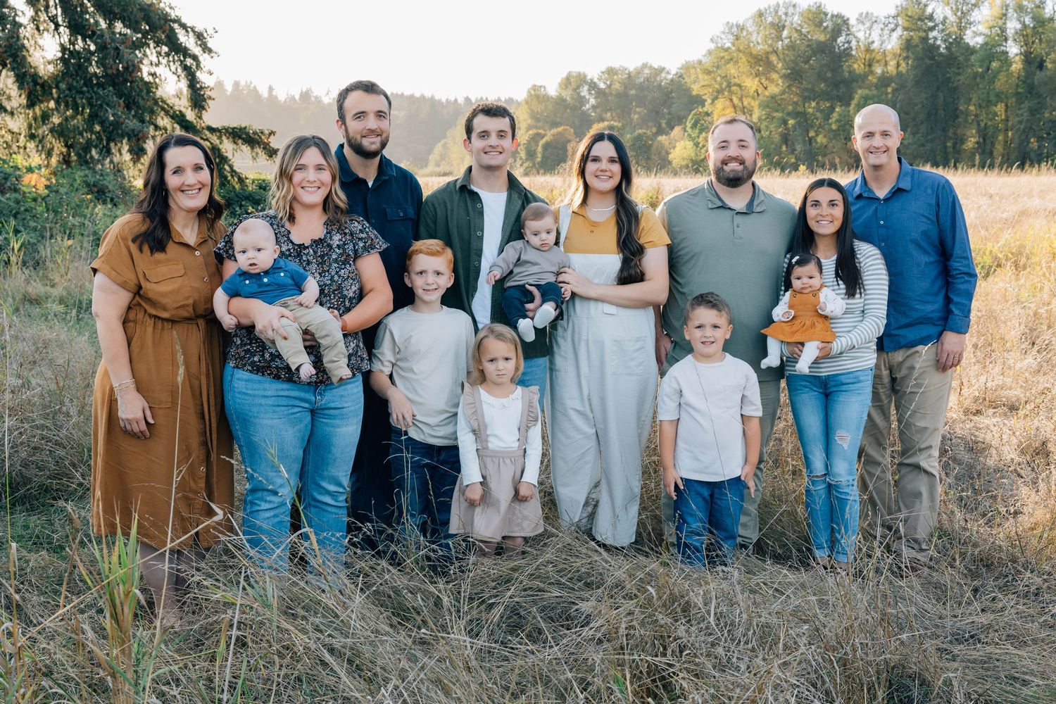 Large extended family posing together in a golden field during an outdoor photo session.