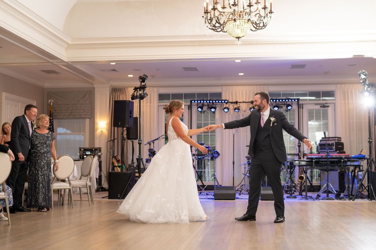 A romantic first dance moment at an elegant wedding reception with chandelier lighting.