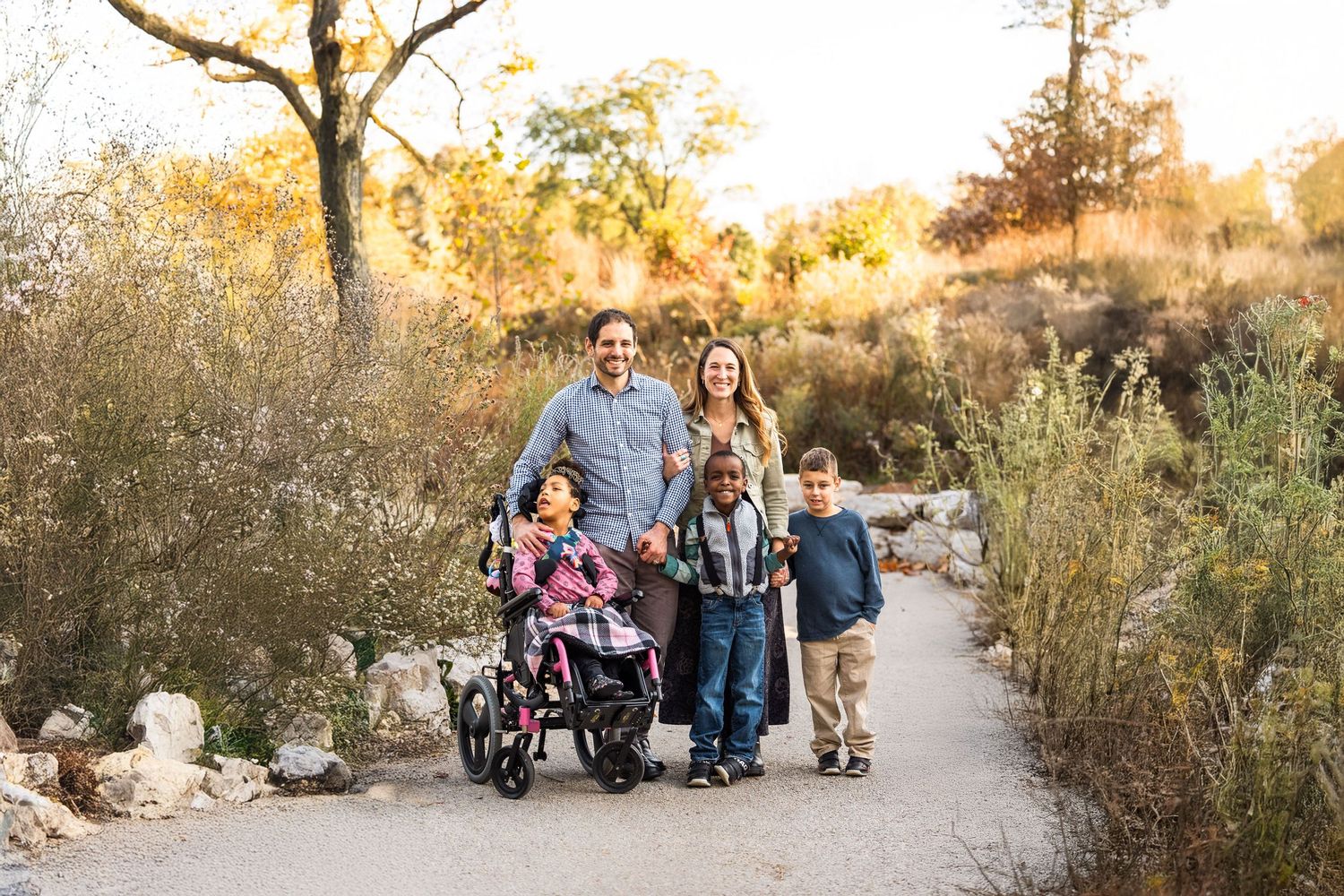 Group walking together on a winding nature trail during golden hour with trees in the background.