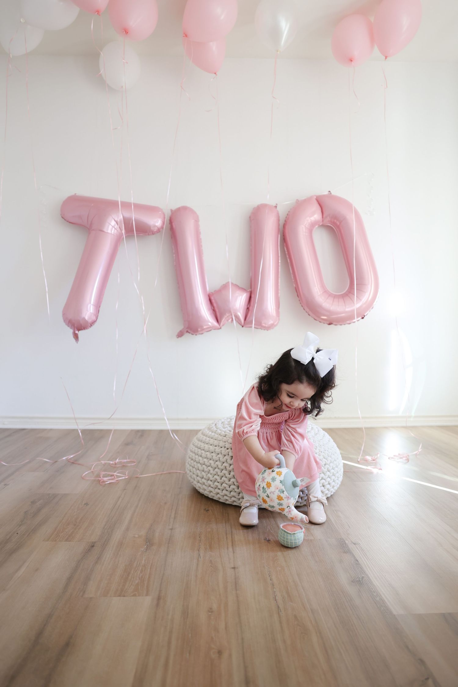 A toddler playing with her tea set during her milestone 2nd birthday photo session indoors during January in Austin, TX.