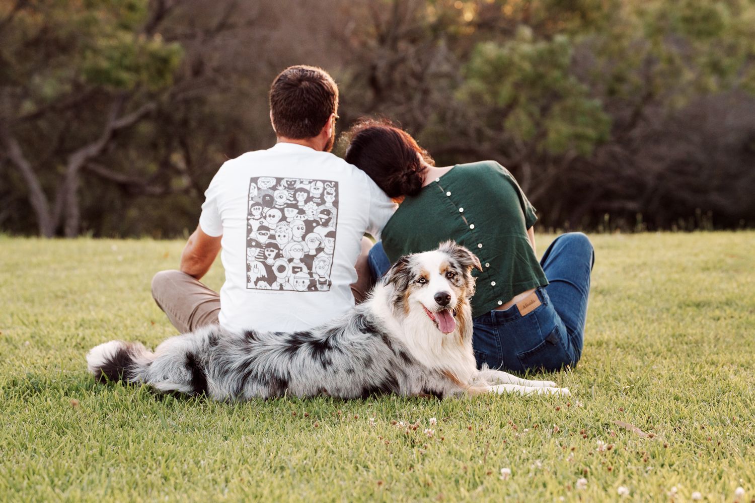 a couple looking towards the park and their dog resting right next to them looking at the camera photoshoot in Mosman