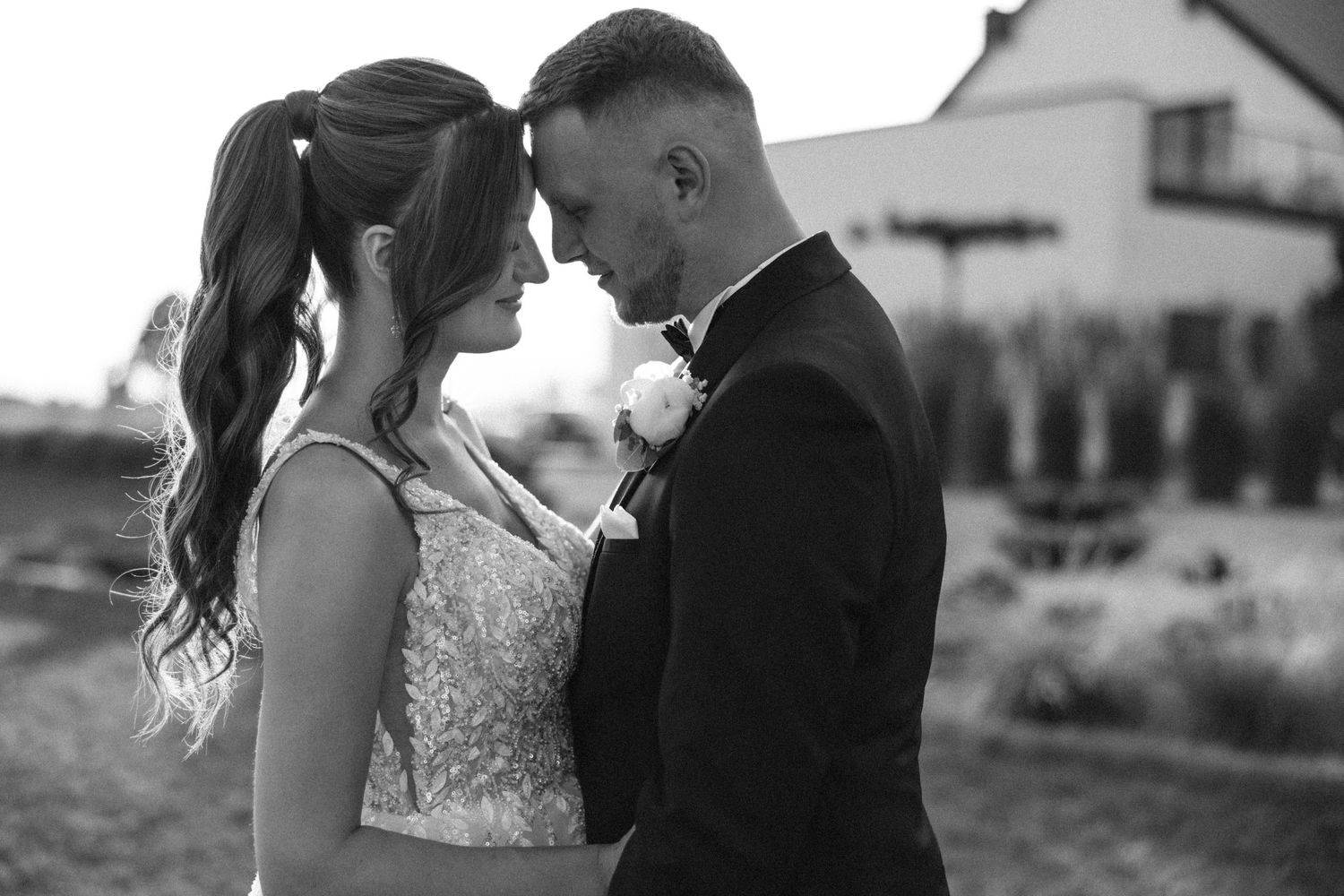 Black and white intimate wedding portrait in natural outdoor setting.