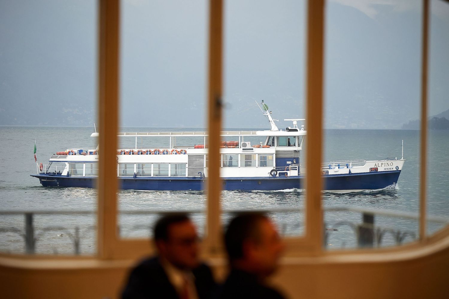 A boat visible through window frames with silhouettes in the foreground.