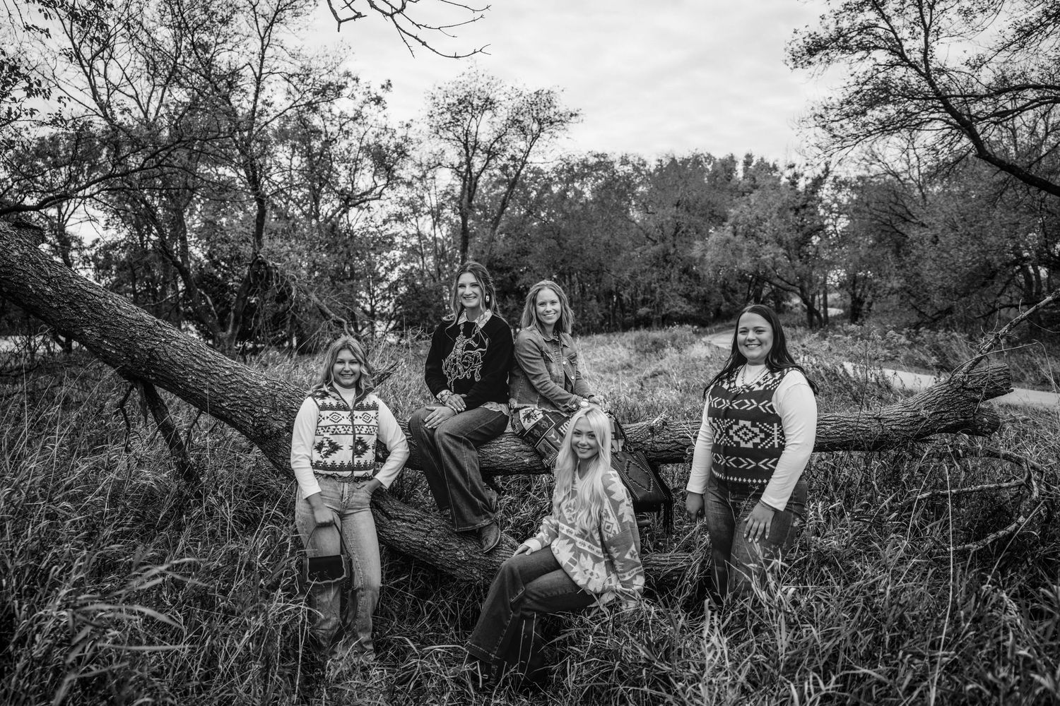 A series of black and white outdoor family portrait photographs taken in a natural wooded setting.