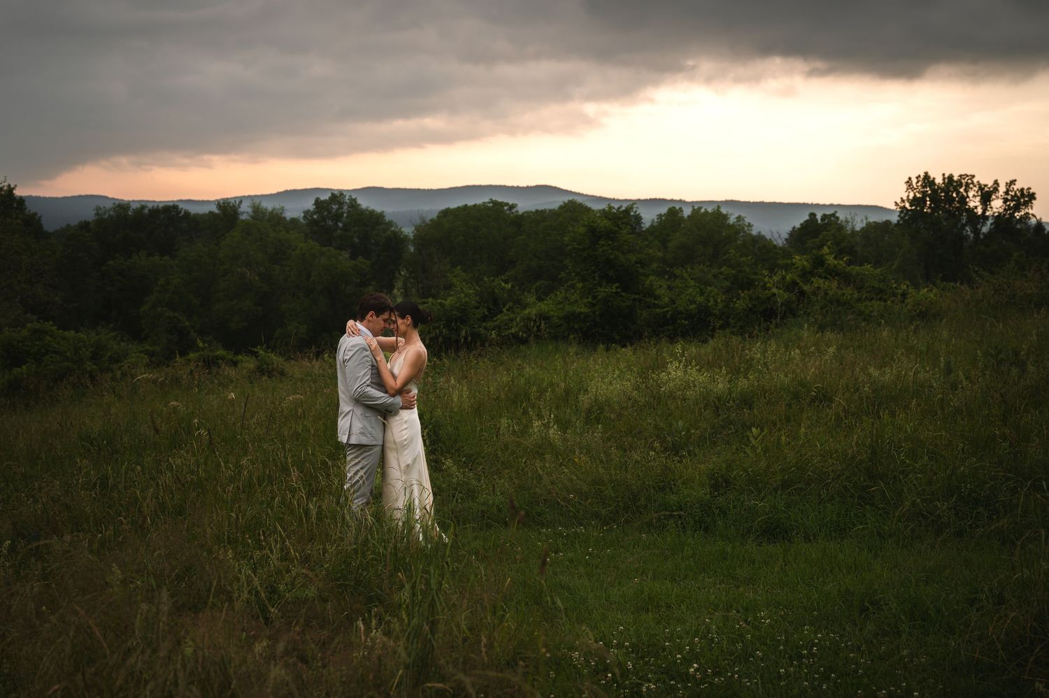 Couple holds hands and walks up stone steps at sunset in summer engagement session at Little Stony Point in Cold Spring, NY in Hudson Valley