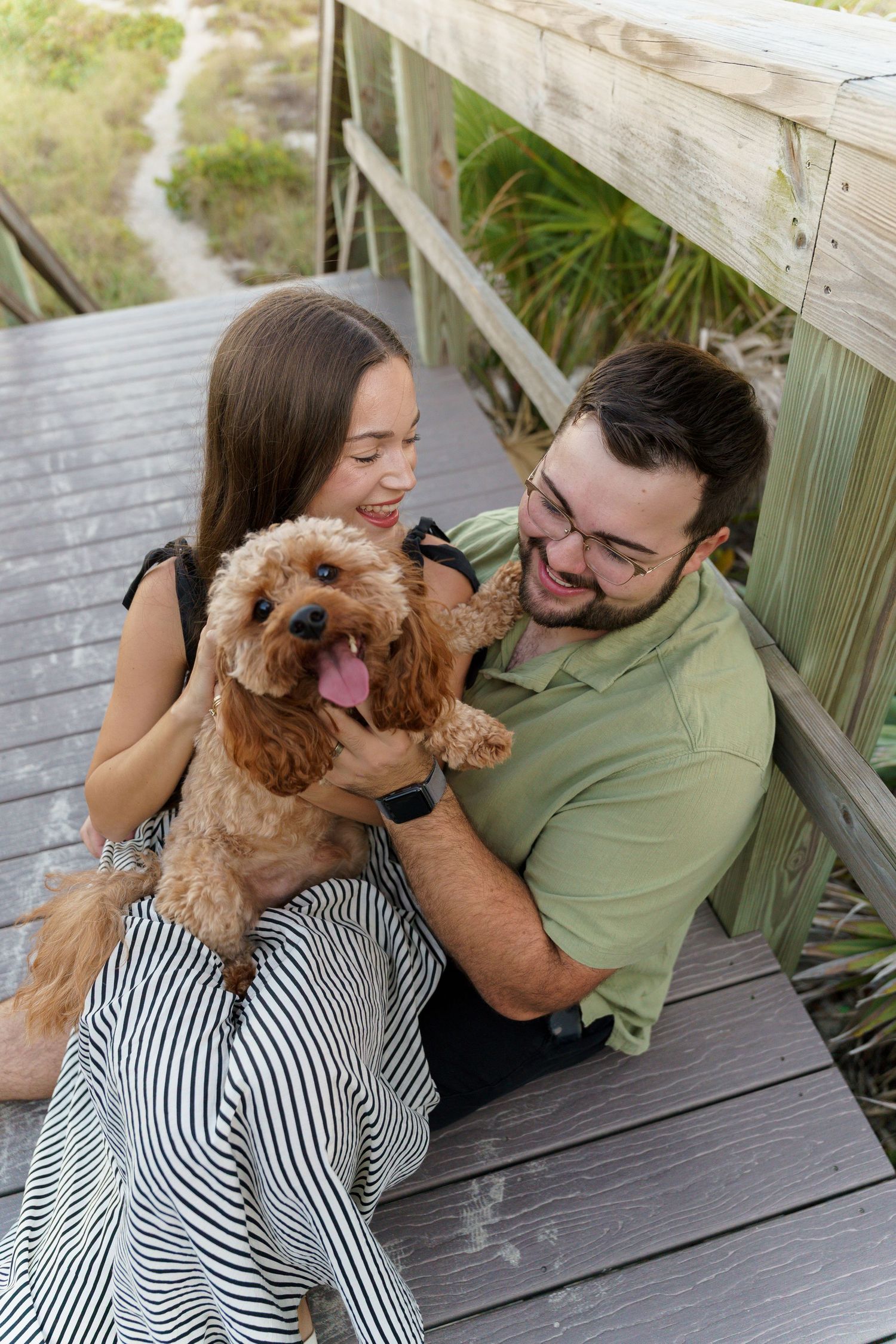 A couple and their fluffy brown dog share playful moments on a wooden deck in a series of candid photos.