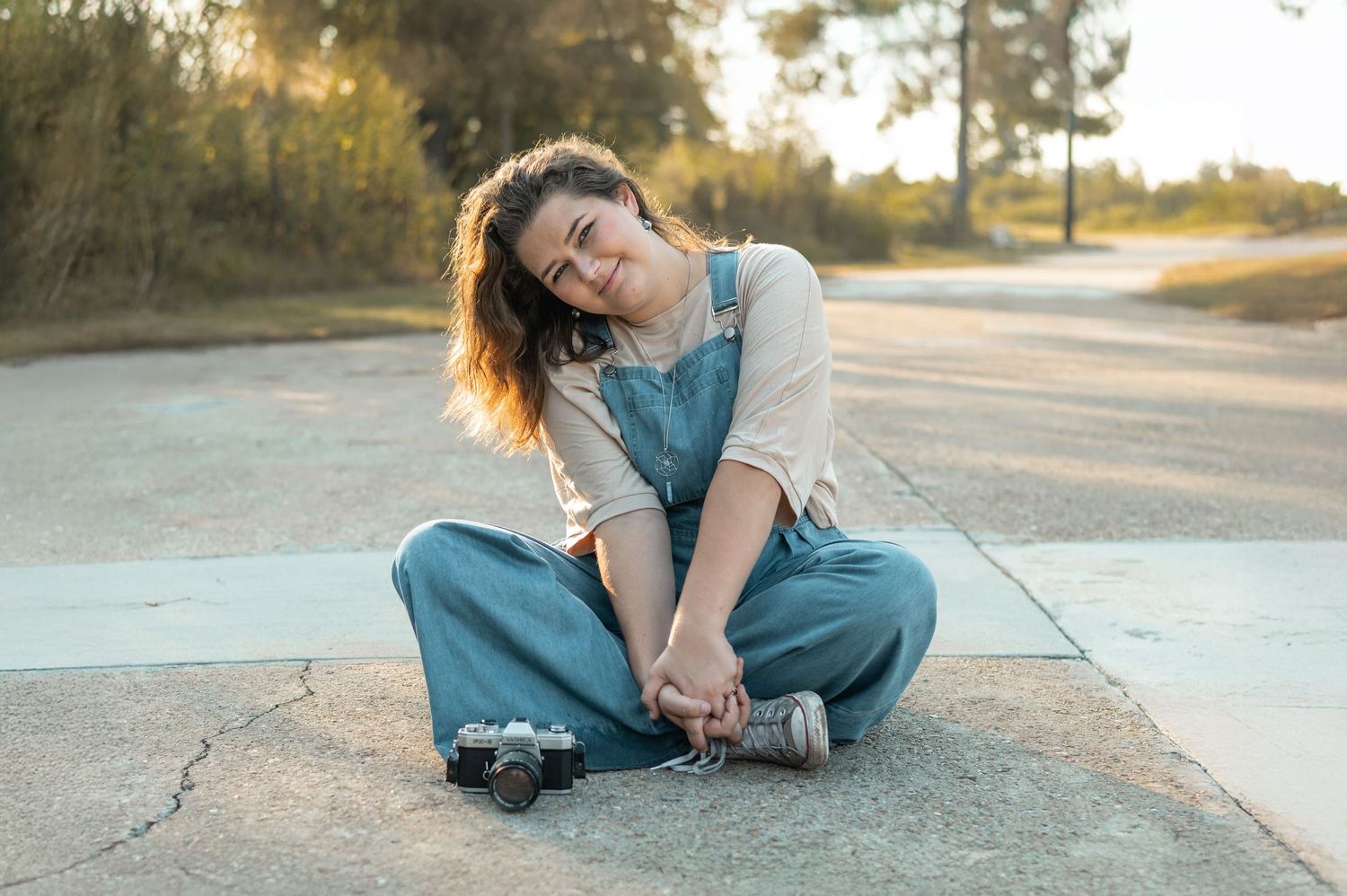 Person wearing denim sits on asphalt road during golden hour sunset creating artistic portrait series.