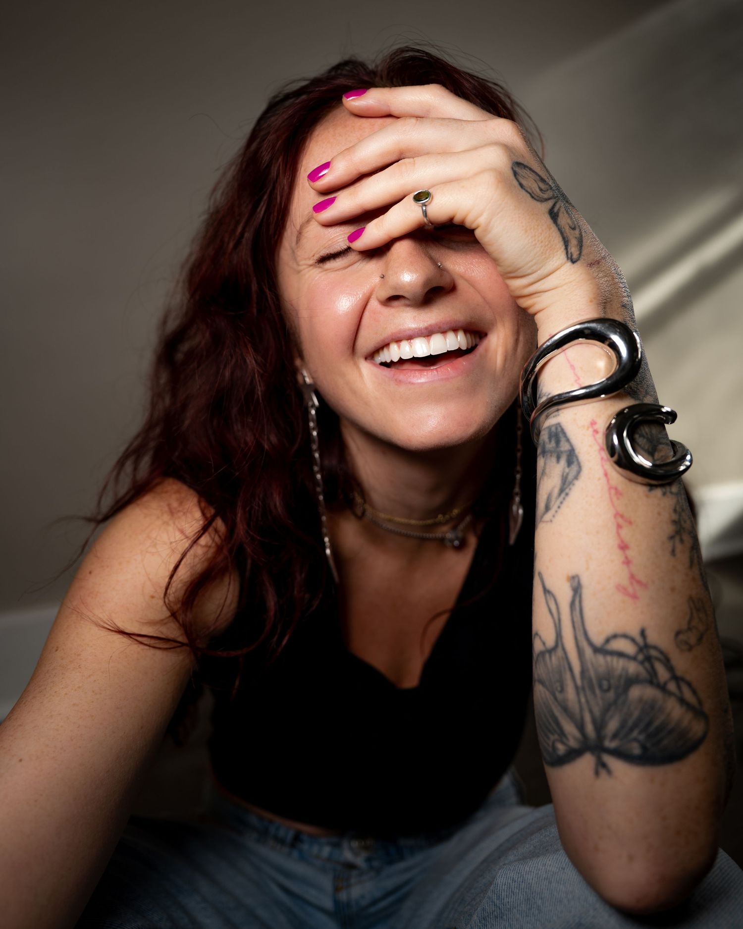 A series of photos showing someone laughing while covering their face with a tattooed arm.
