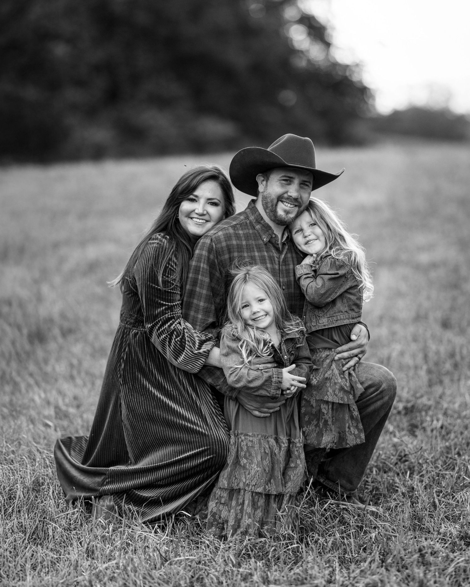 A series of black and white photos showing tender moments between a family lying in a grassy field.