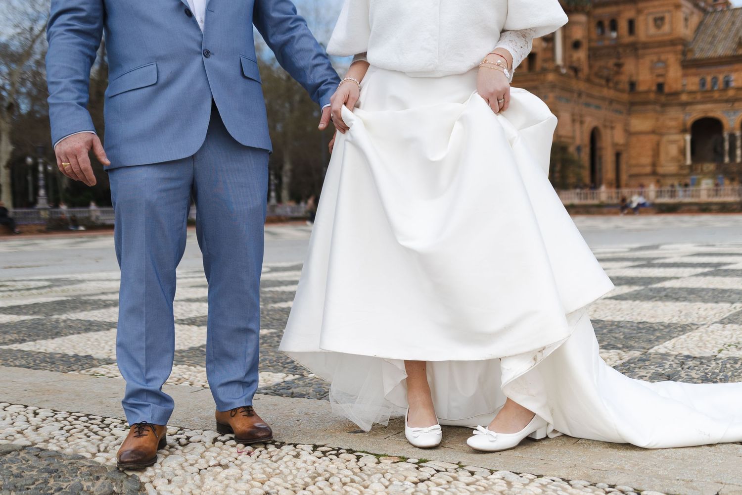 Close-up view of bride and groom's feet on cobblestone pavement during wedding photo session.
