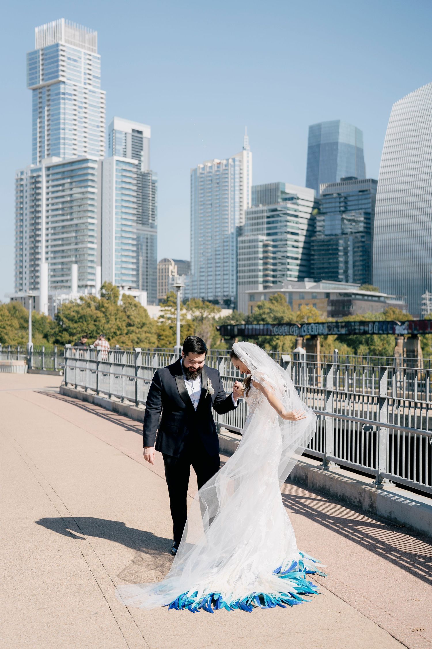 Wedding couple posing along a modern Austin waterfront with high-rise buildings in the background during a destination wedding.