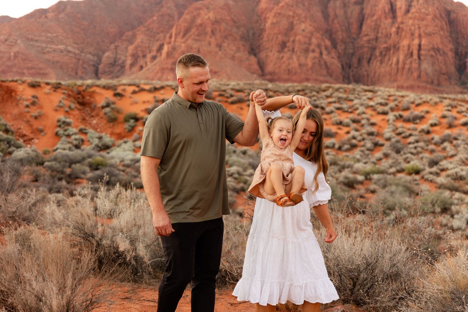 mom and dad holding little girls hand swinging her towards the camera